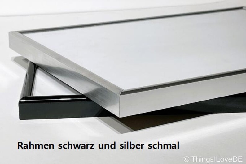 May include: A silver picture frame with a black inner frame. The frame is narrow and has a simple design.