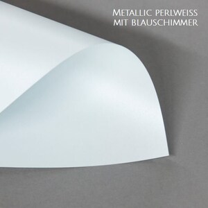 May include: A sheet of metallic pearl white paper with a blue shimmer. The paper is folded in half and the top half is lifted up to show the shimmer.