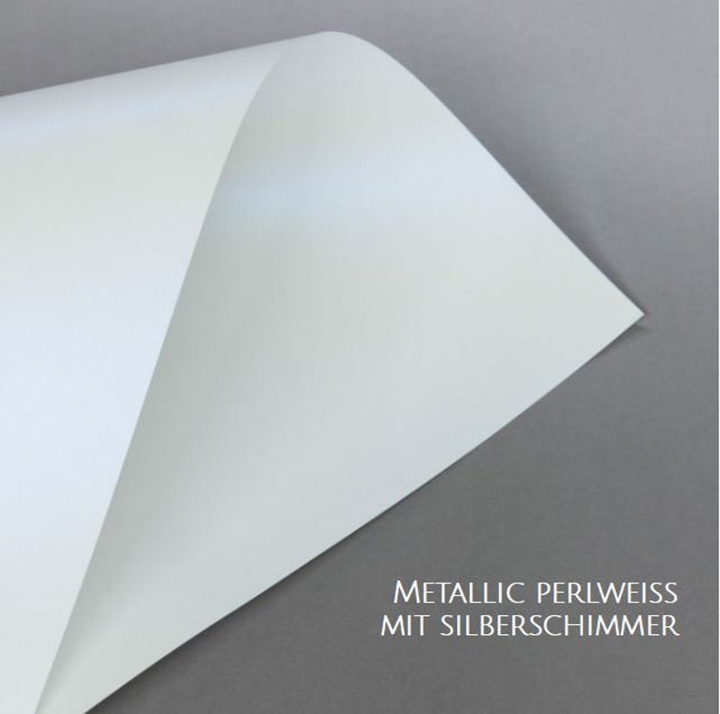 May include: A close-up of a sheet of white paper with a subtle pearlescent sheen. The paper has a slight silver shimmer. The text "METALLIC PERLWEISS MIT SILBERSCHIMMER" is printed at the bottom of the image.