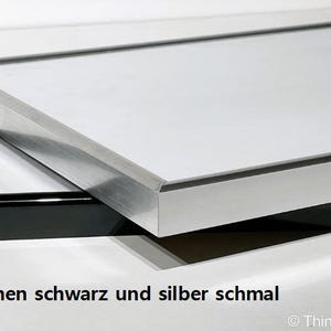 May include: A silver and black picture frame with a narrow border.