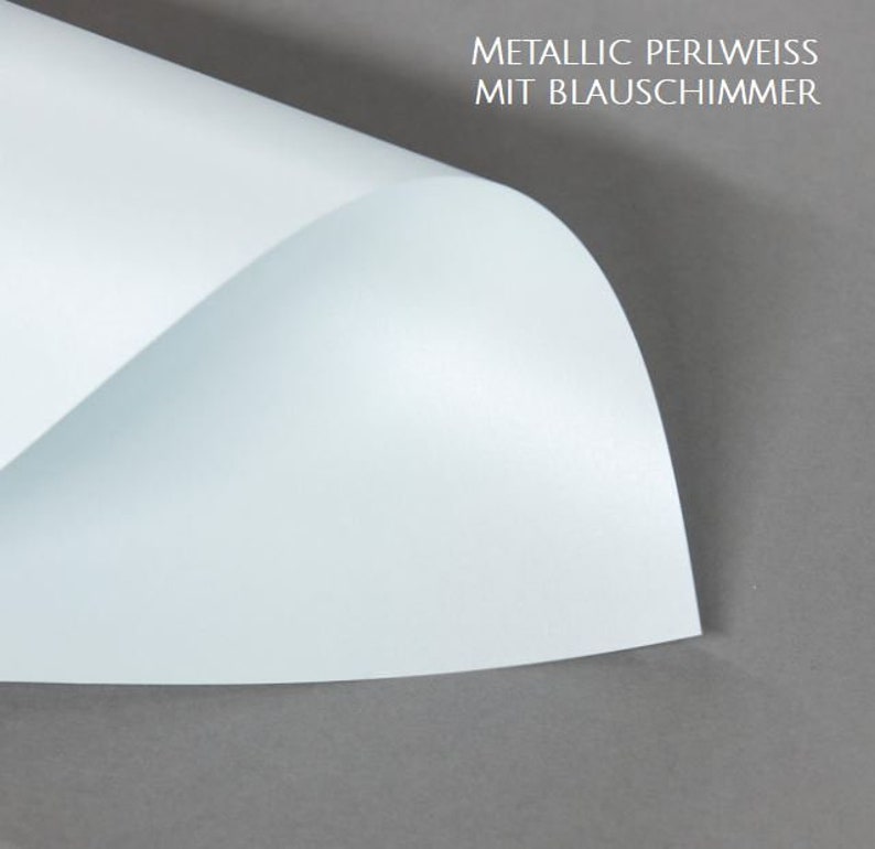 May include: A sheet of metallic pearl white paper with a blue shimmer. The paper is folded in half and the top half is lifted up to show the shimmer.