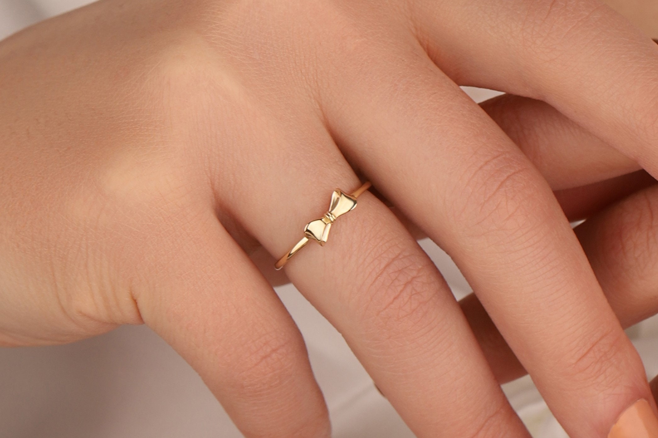 Delicate gold ribbon bow ring close up