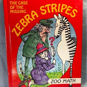 May include: A children's book titled "The Case of the Missing Zebra Stripes" with illustrations of a detective, a cat, and a zebra. The cover is red with yellow and white text and a blue background.