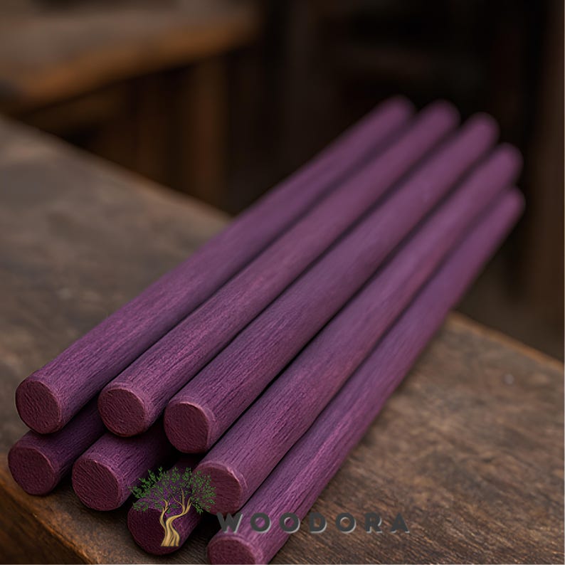 May include: A close-up shot displays several cylindrical wooden dowels, each approximately 12 inches long, dyed a deep purple hue. The wood grain is visible, adding texture. The dowels are arranged on a wooden surface, suggesting a craft or woodworking theme.