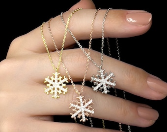 以下が含まれることがあります： キュービックジルコニアの石が付いた、繊細な雪の結晶のネックレスが4つ。ネックレスはゴールド、ローズゴールド、シルバーです。