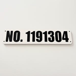 May include: White rectangular sign with black text that reads "NO. 1191304".