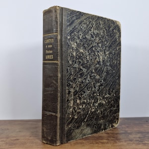 May include: A vintage hardback book with a dark brown cover and gold lettering. The title is "CONTES a une Petite AMIES".