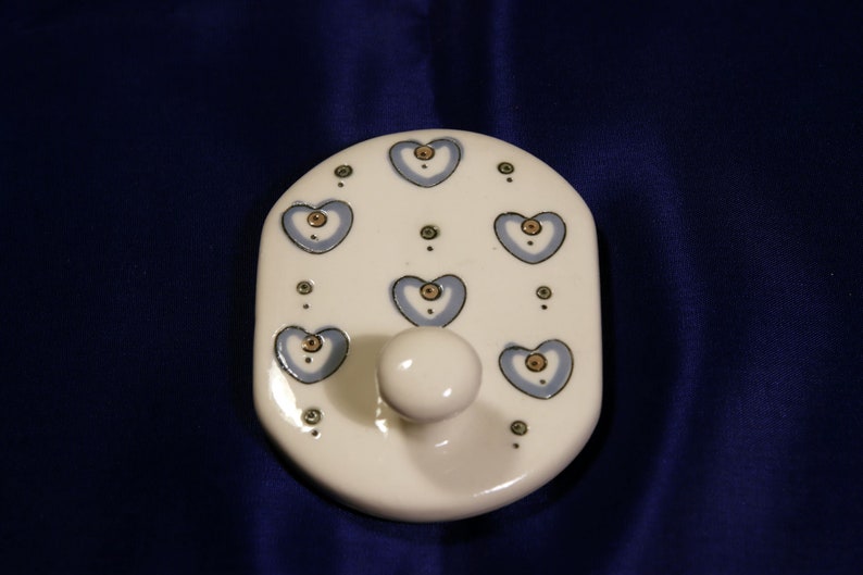 May include: White ceramic hook with a knob and a blue and gold heart pattern.