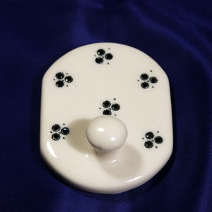 May include: White ceramic hook with a single hook and five black floral designs.