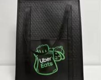 Puede incluir: Bolsa de entrega aislada negra con un logotipo verde de Uber Eats y un personaje de dibujos animados en la parte delantera.