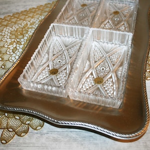 May include: A silver serving tray with four clear glass dishes with intricate cut designs. The dishes are arranged in a square pattern on the tray.