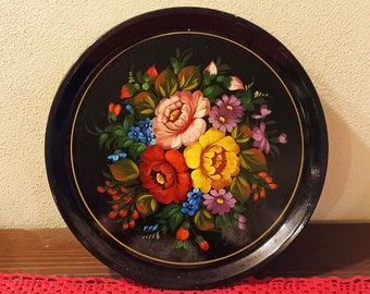 May include: A black round tray with a painted floral design. The flowers are red, yellow, pink, purple, and blue. The tray is perfect for serving snacks or drinks.