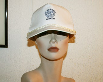 May include: White baseball cap with a blue and green University of Hawaii logo and the text "UNIVERSITY HAWAII".