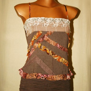May include: A brown sleeveless top with a lace trim and layered fabric details. The top has a ruffled hem and a brown skirt.