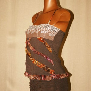May include: A brown sleeveless top with a white lace trim and brown and orange patterned fabric accents. The top has a fitted bodice and a flowing skirt.