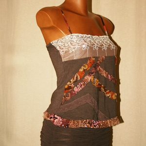 May include: A brown sleeveless top with a lace trim and a brown skirt. The top has a patchwork design with brown, orange, and pink fabric.