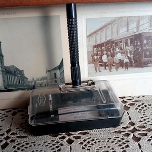 May include: A black safety razor with a clear plastic case. The razor has a black handle with a textured grip and a silver blade. The case has the words "CAUTION" and "WILKINSON" printed on it.