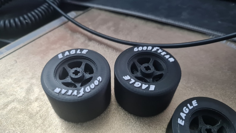 K&ouml;nnte beinhalten: Drei schwarze Gummireifen mit wei&szlig;er Beschriftung. Die Reifen sind mit "Goodyear Eagle" beschriftet und haben ein F&uuml;nf-Speichen-Rad-Design.