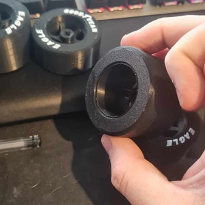 K&ouml;nnte beinhalten: Nahaufnahme eines schwarzen Gummireifens mit dem Wort "EAGLE" auf der Seite. Der Reifen wird von einer Hand gehalten.