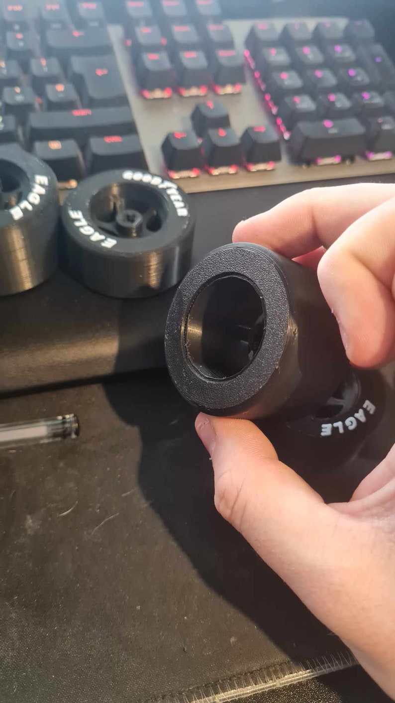 K&ouml;nnte beinhalten: Nahaufnahme eines schwarzen Gummireifens mit dem Wort "EAGLE" auf der Seite. Der Reifen wird von einer Hand gehalten.