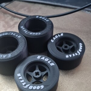 K&ouml;nnte beinhalten: Vier schwarze Goodyear Eagle Reifen mit wei&szlig;er Beschriftung. Die Reifen sind f&uuml;r Modellautos konzipiert.