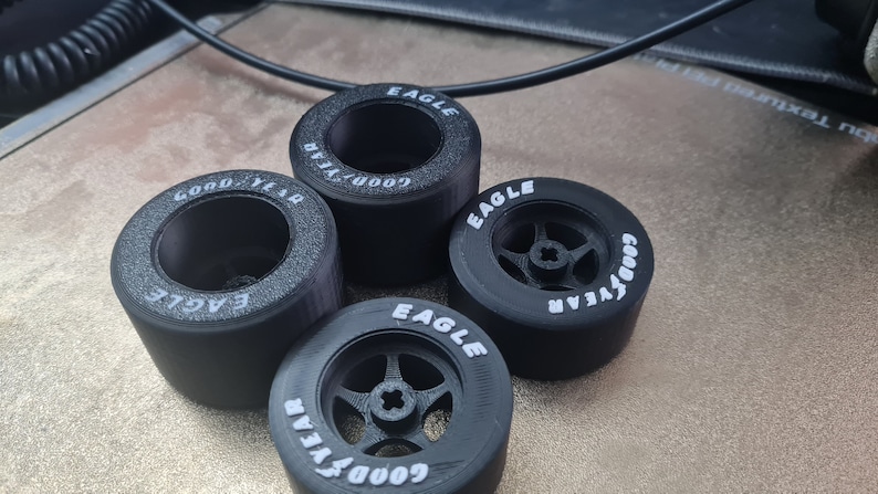 K&ouml;nnte beinhalten: Vier schwarze Goodyear Eagle Reifen mit wei&szlig;er Beschriftung. Die Reifen sind f&uuml;r Modellautos konzipiert.
