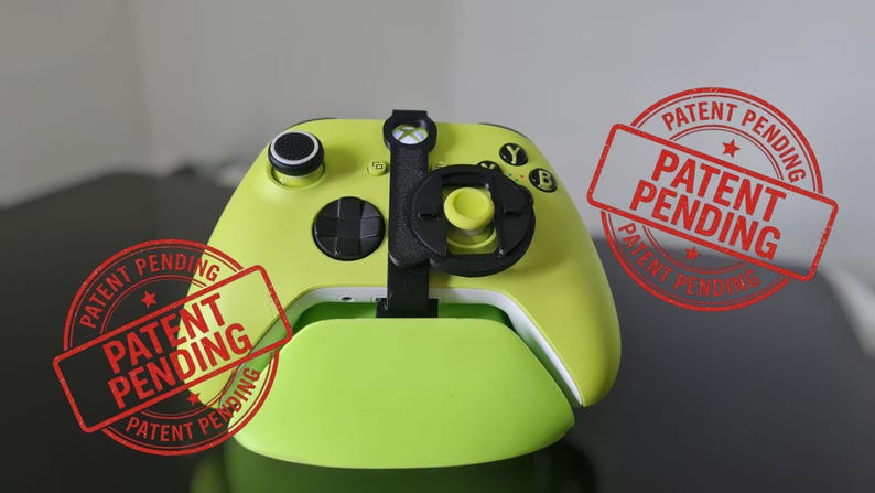 May include: A lime green Xbox controller with black accents and a black attachment. The controller is on a matching green base. The image includes red stamps that say "PATENT PENDING".