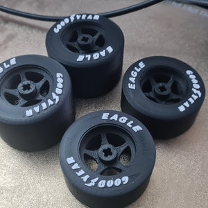 K&ouml;nnte beinhalten: Vier schwarze Goodyear Eagle Reifen mit wei&szlig;er Beschriftung. Die Reifen sind f&uuml;r ein Modellauto.