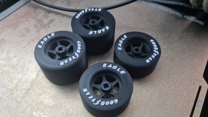 K&ouml;nnte beinhalten: Vier schwarze Goodyear Eagle Reifen mit wei&szlig;er Beschriftung. Die Reifen sind f&uuml;r ein Modellauto.