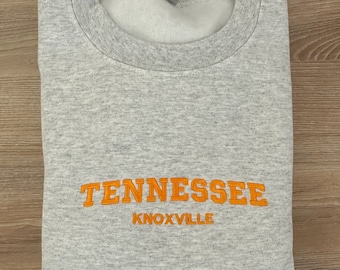 May include: Gray sweatshirt with orange embroidered text that reads "Tennessee Knoxville".
