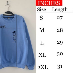 Pu&ograve; includere: Una felpa di colore blu chiaro con una tabella delle taglie che mostra le misure in pollici per le taglie S, M, L, XL e 2XL. La tabella mostra le misure del petto e della lunghezza.