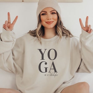 Peut inclure: Un sweat-shirt beige avec le texte "YOGA is a lifestyle" imprim&eacute; sur le devant.
