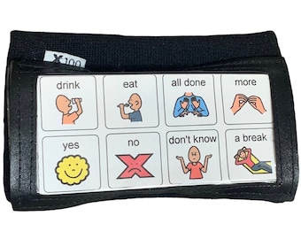 May include: Black wristband with a clear plastic window displaying eight white squares with black outlines. Each square contains a picture and text. The text includes "drink", "eat", "all done", "more", "yes", "no", "don't know", and "a break".