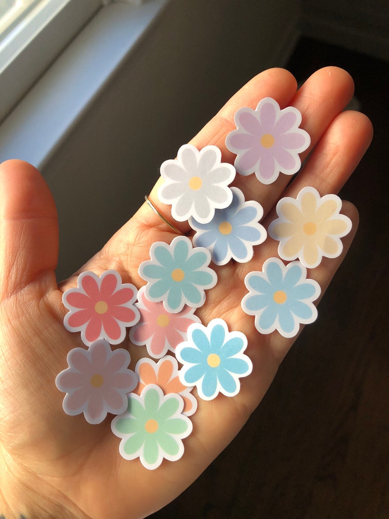 Puede incluir: Una colecci&oacute;n de pegatinas de flores de color pastel. Las pegatinas son de varios tonos de rosa, azul, amarillo y verde.