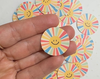 May include: A pile of colourful round stickers with a yellow smiley face in the centre of each sticker. The stickers have a rainbow striped design.