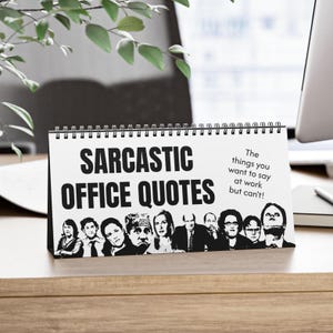 以下が含まれることがあります： 「SARCASTIC OFFICE QUOTES」の文字と「The things you want to say at work but can't!」というフレーズが黒で書かれた卓上カレンダー。カレンダーには、さまざまな人々の白黒イラストが描かれています。