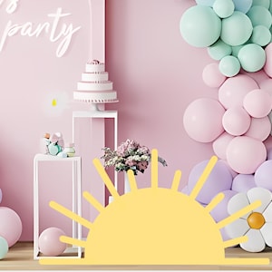 Può includere: Sfondo rosa per feste con torta a più livelli, palloncini e decorazioni floreali. Le parole "let's party" sono scritte in bianco. Una grande forma di sole giallo è in primo piano, creando un'atmosfera festosa.