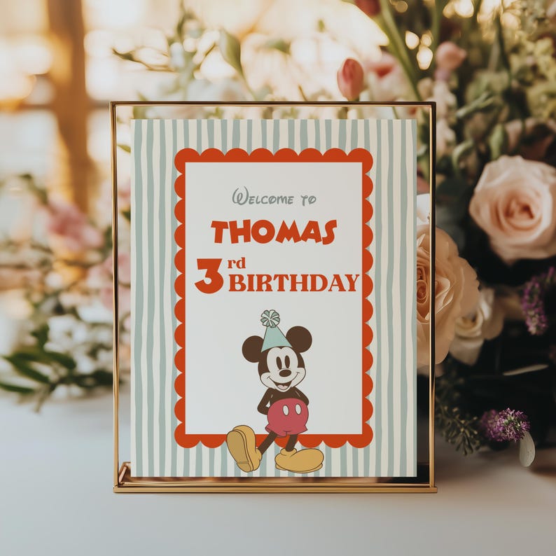 Puede incluir: Un letrero de cumplea&ntilde;os enmarcado con un borde dorado. El letrero tiene un borde rojo festoneado y un fondo a rayas azul claro y blanco. El texto dice "Bienvenido al 3er cumplea&ntilde;os de Thomas" con un gr&aacute;fico de Mickey Mouse.