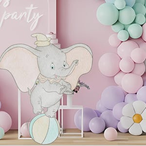 May include: A whimsical party scene featuring a Dumbo the elephant illustration balancing on a ball. Pastel balloons in pink, purple, and mint green create a festive backdrop. The words "let's party" are written in cursive on the wall.