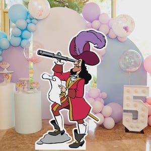 Puede incluir: Un recorte de cartón del Capitán Garfio se encuentra frente a un telón de fondo de fiesta con globos. El recorte lleva un abrigo rojo, un sombrero morado y sostiene un catalejo y un pergamino. El número 5 está iluminado en el fondo.