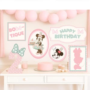 Könnte beinhalten: Eine Minnie-Maus-Geburtstagsparty-Dekoration mit rosa und mintgrünen Dekorationen. Enthält einen Kuchen, Cupcakes und Schilder mit den Aufschriften "BOUTIQUE" und "HAPPY BIRTHDAY". Eine große "2" ist mit Polka-Dots verziert.