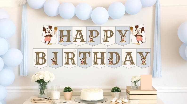 May include: A festive birthday party scene with a banner that reads "HAPPY BIRTHDAY" in brown letters. Mickey Mouse illustrations are featured on the banner. Light blue balloons and decorations are also present. A cake and cupcakes are on the table.