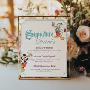 Pode incluir: Uma placa com moldura dourada com as palavras "Signature Drinks" em escrita turquesa. A placa lista três receitas de bebidas: Donald's Berry Fizz, Mickey's Tropical Splash e Minnie's Lemonade Twist. Apresentam-se imagens de desenhos animados do Pato Donald e Mickey Mouse.