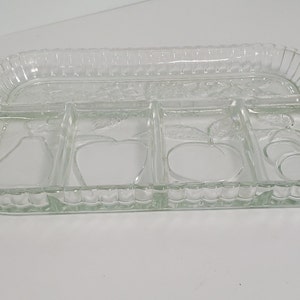 May include: Clear glass serving tray with a rectangular shape and divided sections. The tray features embossed fruit designs and a ribbed edge. Includes handles on each end.