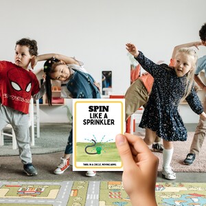 May include: A yellow card with the text "SPIN LIKE A SPRINKLER" and a cartoon illustration of a sprinkler. The text below the illustration reads "TWIRL IN A CIRCLE, MOVING ARMS."