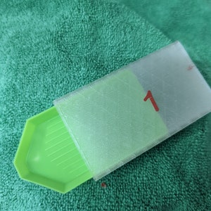 Puede incluir: Una bandeja de pintura de diamantes verde con una tapa de pl&aacute;stico transparente etiquetada con el n&uacute;mero "1".