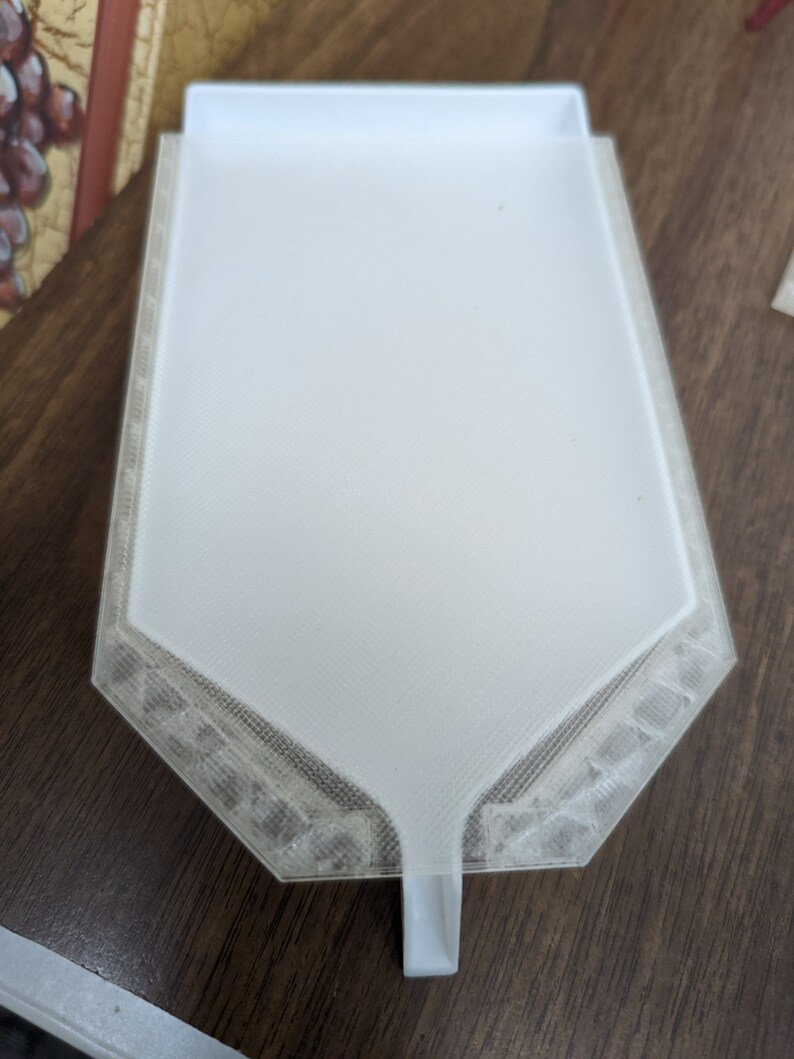 Puede incluir: Un embudo de pl&aacute;stico blanco con una base hexagonal y un pico. El embudo est&aacute; dise&ntilde;ado para verter l&iacute;quidos en recipientes con aberturas estrechas.