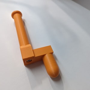 May include: An orange plastic toilet paper holder with a rounded end. The holder is mounted to a wall.