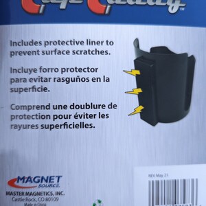 Op de afbeelding: Een zwarte magnetische bekerhouder met een beschermende voering om krassen op oppervlakken te voorkomen. De verpakking toont de productnaam, drie gele bliksemschichtpictogrammen die naar de magneet wijzen en een barcode met nummer 0 95421 07583 6.