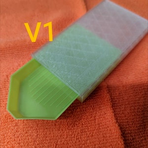 Puede incluir: Una bandeja de pintura de diamantes verde con una tapa de pl&aacute;stico transparente. La tapa tiene un patr&oacute;n de cuadr&iacute;cula y la bandeja tiene una superficie estriada. El texto "V1" es visible en la imagen.